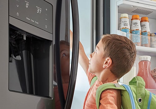 Young Boy Opens Black Stainless Steel Refridgerator