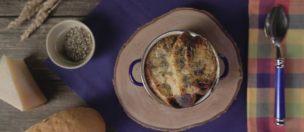 Rich French onion soup with melted Gruyere cheese garnished with minced shallots on a wooden serving plate.  Recipe calls for 12 ingredients, 165 minutes cooking time, 10 minutes prep time, and 2 servings.