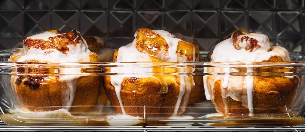 3 warm and gooey cinnamon rolls in a glass dish covered in icing and topped with orange zest.  Recipe calls for 11 ingredients, 40 minutes cooking time, 45 minutes prep time, and 8 servings.