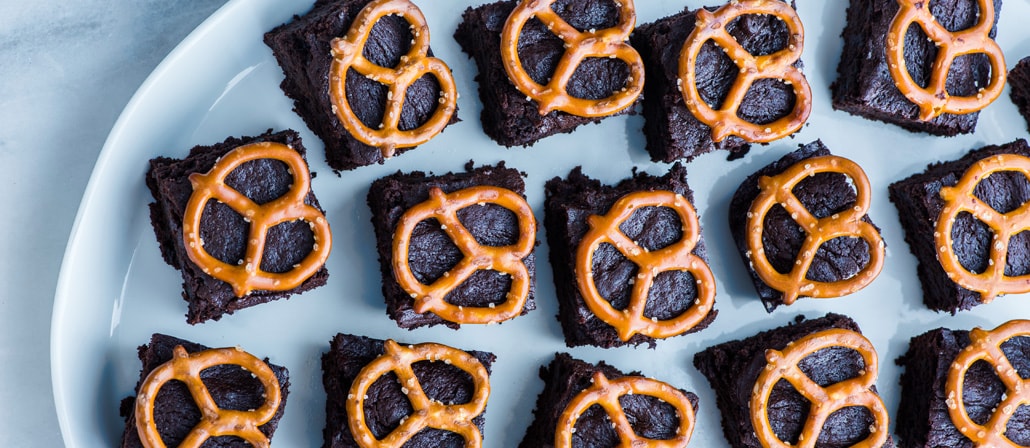 Pretzel Brownies on a plate.  Recipe calls for 13 ingredients, 50 minutes cooking time, 15 minutes prep time, and 25 servings.