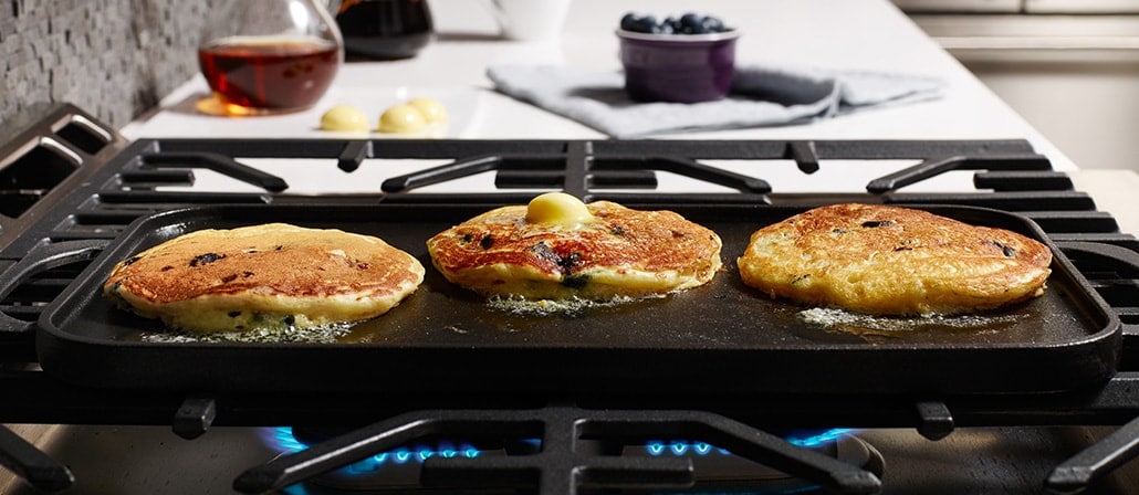 Blueberry pancakes topped with melted butter on the griddle on the stovetop.  Recipe calls for 10 ingredients, 10 cooking time, 5 minutes prep time, and 4 servings.
