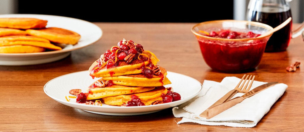 Pumpkin Pancakes with Cranberry Topping on a plate.  Recipe calls for 10 ingredients, 30 minutes cooking time, 15 minutes prep time, and 4 servings.