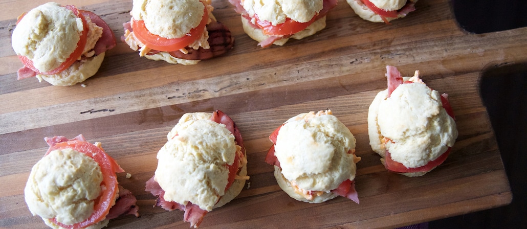 8 buttermilk biscuits on a wooden serving board with tomatoes, ham and cheese.  Recipe calls for 19 ingredients, 15 minutes cooking time, and 10 servings.