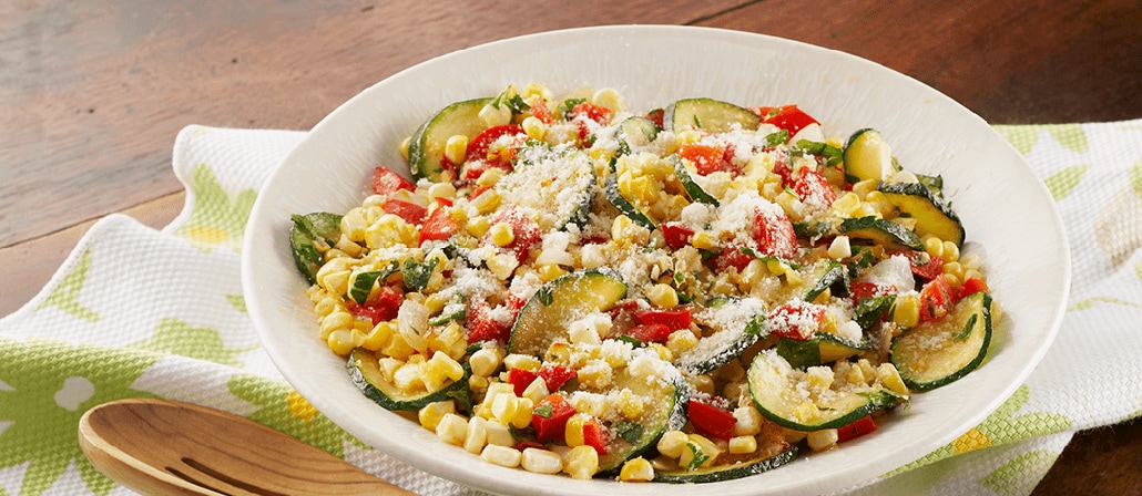 Bowl of Farmers' Market Corn Toss with sweet onion, red pepper, zucchini, fresh parsley and corn.  Recipe calls for 8 ingredients, 25 minutes cooking time, 25 minutes prep time, and 6 servings.