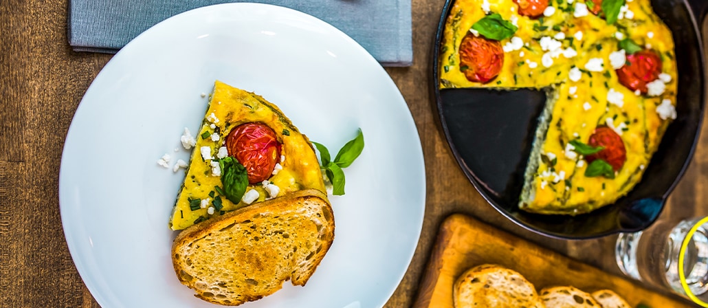 Omelette with asparagus, cherry tomatoes, goat cheese and fresh basil on a plate.  Recipe calls for 9 ingredients, 25 minutes cooking time, 10 minutes prep time, and 4 servings.