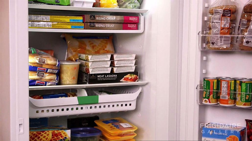 Filled open refrigerator showing a ton of space for leftovers.