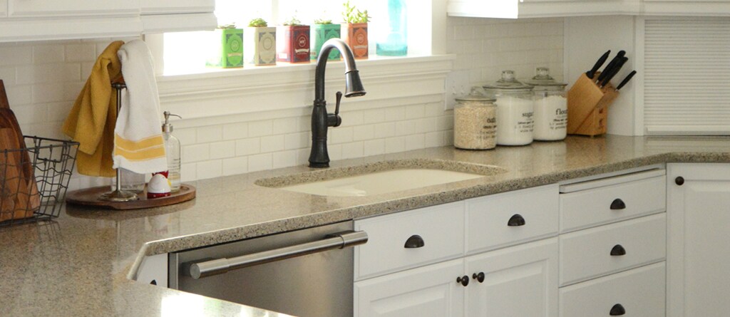 Spacious kitchen with granite countertops, cutlery set and a large window with tons of sunlight shining through.