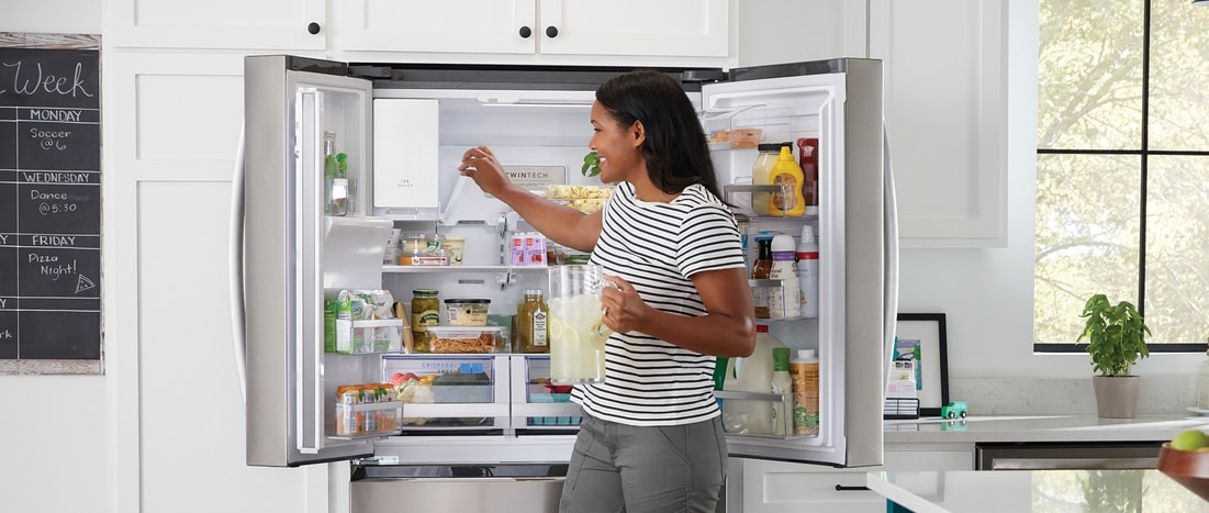 Image of open refrigerator and woman getting ice