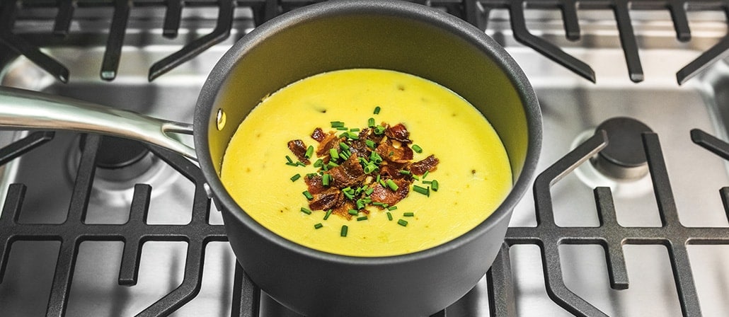 Saucepan on the stove filled with gruyere cheese, cheddar cheese, Monterey jack cheese, bacon and chives.  Recipe calls for 12 ingredients, 40 cooking time, 10 minutes prep time, and 4 servings.