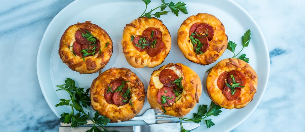 6 Deep-Dish Muffin Tin Pizzas on a serving plate garnished with parsley.  Recipe calls for 17 ingredients, 139 minutes cooking time, 120 minutes prep time, and 12 servings.