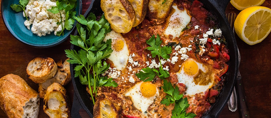 Shakshuka in a cast-iron skillet with garlic bread.  Recipe calls for 14 ingredients, 30 minutes cooking time, 10 minutes prep time, and 4 servings.