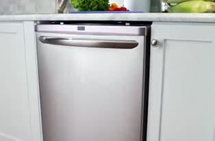 Stainless Steel That's Truly Stainless! - A young woman is baking in her Frigidaire Gallery stainless steel oven. She notices some of the baking mix drips on the oven and wipes it away with ease.