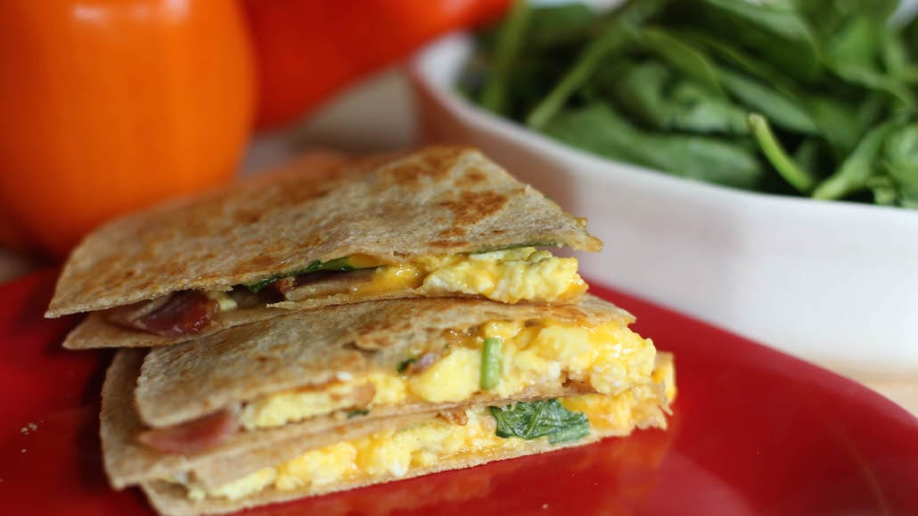 Breakfast Quesadillas on whole-wheat tortillas with scrambled eggs, shredded cheddar cheese, spinach, bacon and diced ham.  Recipe calls for 8 ingredients, 10 minutes cooking time, 5 minutes prep time, and 6 servings.